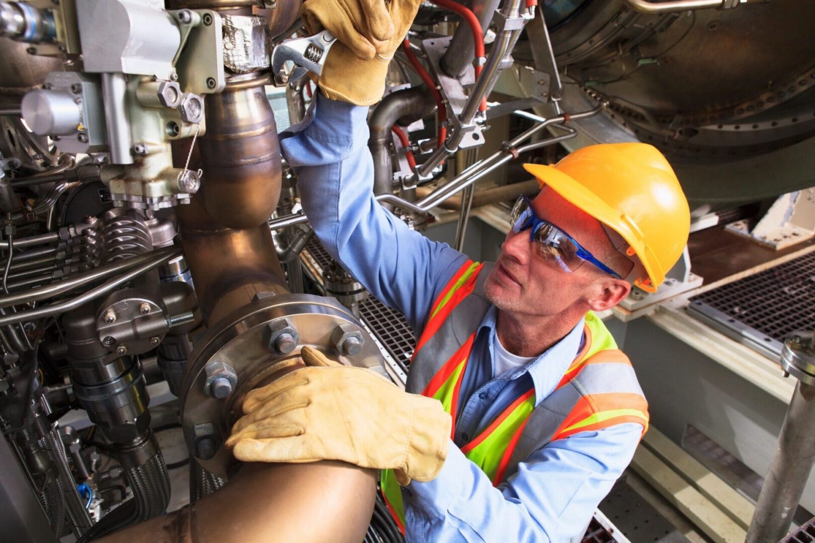 A man in safety gear working on pipes.